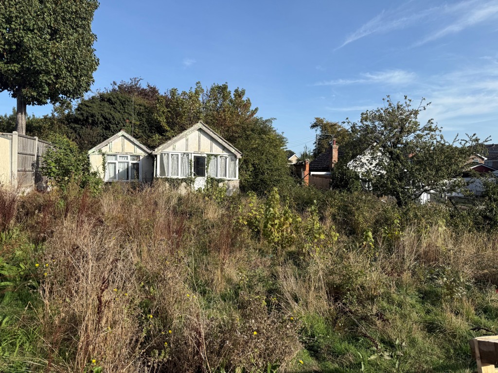 Lot: 55 - ONE-BEDROOM DETACHED COTTAGE FOR DEMOLITION ON APPROXIMATELY 0.14 ACRES OF LAND - Overview shot of overgrown land and building